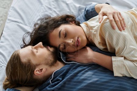 Una pareja amorosa se acurruca en la cama en casa, disfrutando de un momento de paz juntos.