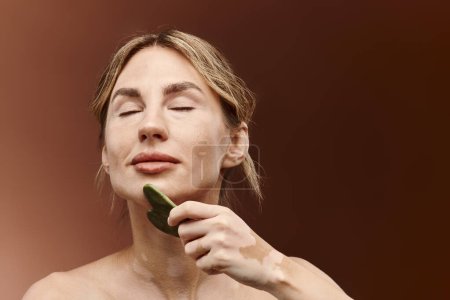 A young woman with vitiligo uses a jade stone for a relaxing beauty routine.