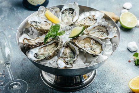 Photo for Oysters on metal tray with ice, lemon and champagne in restaurant. banner, menu, recipe place for text, top view. - Royalty Free Image