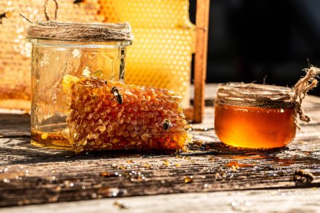 Natürliche Honigwaben und ein Glas auf einem Holztisch. Honig im Hintergrund. Bienenprodukte nach biologischen natürlichen Zutaten Konzept, Nahaufnahme.
