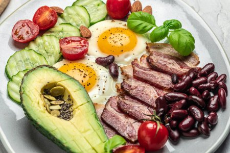 Photo for Keto breakfast with avocado, fried eggs, bacon, and beans. paleo keto breakfast diet lunch. Healthy nutritious paleo keto breakfast concept. Food recipe background. Close up, - Royalty Free Image