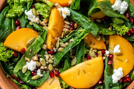 Photo for Gourmet salad with persimmon, avocado, pumpkin seeds, walnuts, pomegranate and arugula on a light background, Flat lay. Banner. Top view. - Royalty Free Image