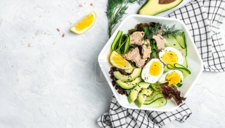 Photo for Ketogenic low carbs diet, Plate with keto foods: two eggs, avocado, tuna, cucumber and fresh salad. Healthy fats, clean eating for weight loss. top view. - Royalty Free Image