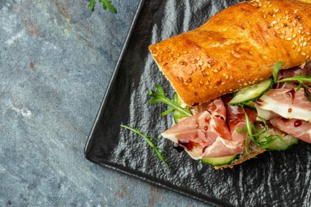 Photo for Ciabatta sandwich with jamon ham serrano paleta iberica, arugula, Mediterranean appetizer. Delicious breakfast or snack, top view. - Royalty Free Image
