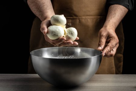 Photo for A man working in a small family creamery is processing the final steps of making a cheese. Italian hard cheese silano or caciocavallo, mozzarella. - Royalty Free Image