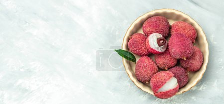 Foto de Lichi maduro. Frutas asiáticas exóticas en un tazón en un plato sobre un fondo claro, formato de bandera larga. vista superior, - Imagen libre de derechos