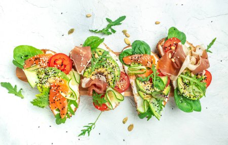 Open sandwich set with cream cheese, prosciutto, salmon, avocado and fresh greens. Keto, ketogenic diet, low carb, high good fat , healthy food. top view.