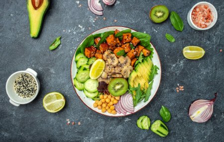 Téléchargez les photos : Healthy vegetable lunch in a Buddha bowl with tofu, avocado, chickpeas, cucumber and mushrooms, banner, menu, recipe place for text, top view, - en image libre de droit