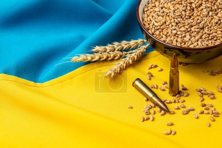 Bullets and Grain on yellow blue Ukrainian state flag background. Concept of food supply crisis and global food scarcity. place for text, top view