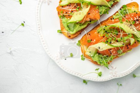 Photo for Sandwich with cream cheese, salmon, avocado, cucumber, tomato and greens on a light background. Keto breakfast or brunch. banner, menu, recipe place for text, top view. - Royalty Free Image