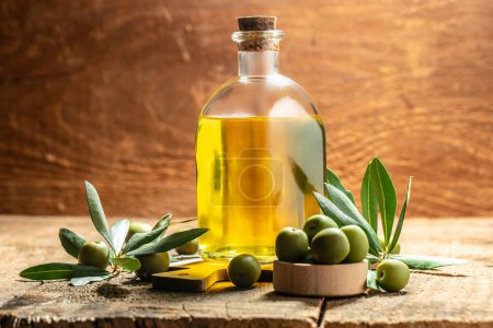 Foto de Aceite de oliva en frascos con aceitunas y hojas negras y verdes. frascos de aceite de oliva virgen extra sobre un fondo de madera. lugar para el texto. - Imagen libre de derechos