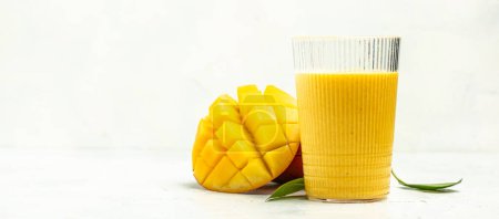 Mango Lassi, yogurt or smoothie with turmeric. Fresh tropical fruit on a white background. Long banner format.