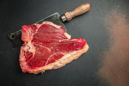 Roh Porterhouse Steak von Premium-Rindfleisch mit einem Fleischspalter auf schwarzem Stein Hintergrund. Rohes Rindfleisch. Platz für Text, Draufsicht.