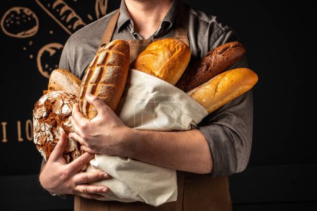 Photo for Man holding breas in his hands. Different types of bread. bakery products on a dark background. Long banner format. - Royalty Free Image