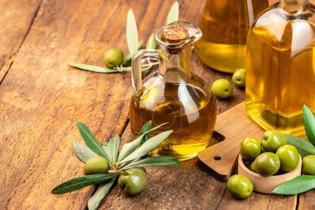Foto de Aceite de oliva y rama de olivo. frascos de aceite de oliva virgen extra sobre un fondo de madera. lugar para el texto. - Imagen libre de derechos