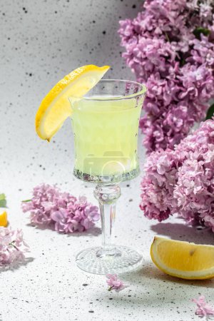 Photo for Traditional liqueur limoncello with blooming lilac on a light background, - Royalty Free Image