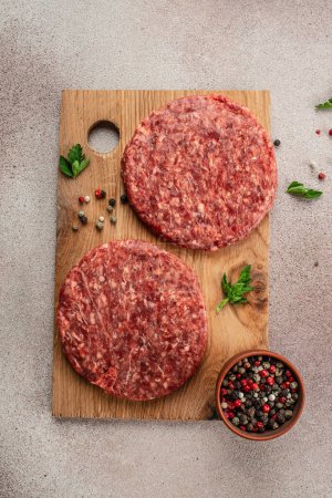 Téléchargez les photos : Viande de bœuf hachée crue côtelettes de steak burger sur une planche en bois, fond de recette alimentaire. Gros plan, image verticale. vue de dessus. place pour le texte, - en image libre de droit