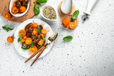 Tomato Salad with cherry red and yellow tomatoes, topping balsamic sauce and basil on a light background, place for text, top view,