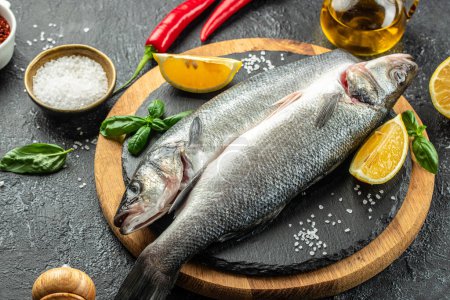 Photo for Raw fish sea bass with ingredients on a dark background. banner, menu, recipe place for text, top view. - Royalty Free Image