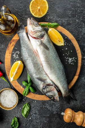Photo for Raw fish sea bass with ingredients on a dark background. vertical image. top view. place for text. - Royalty Free Image