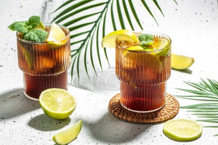 Photo for Cuba Libre with Lime and Ice mint in the glass on a light background top view. copy space. - Royalty Free Image