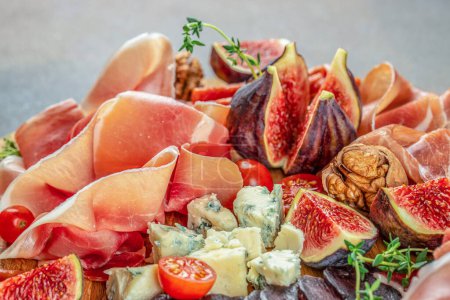 Prosciutto with figs and cheese. Dinner or aperitivo party concept. Restaurant menu, dieting, cookbook recipe top view.