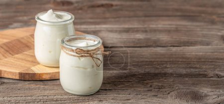 Jars of tasty yogurt on a wooden background. The concept of a lactose-free dairy product, copy space,