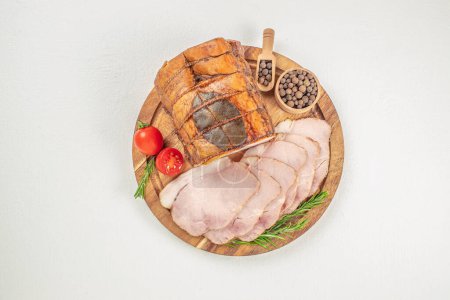 Sliced smoked ham with herbs and aromatic spices on plate.