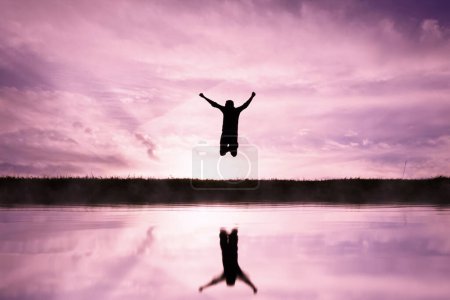 man jumping over a pond with a sunset background 