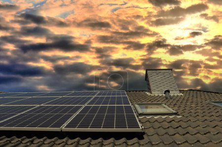 Photo for Solar panels producing clean energy on a roof of a residential house during sunset - Royalty Free Image