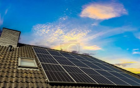 Solar panels producing clean energy on a roof of a residential house during sunset