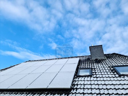 Photo for Snow covered solar panels producing clean energy on a roof of a residential house - Royalty Free Image