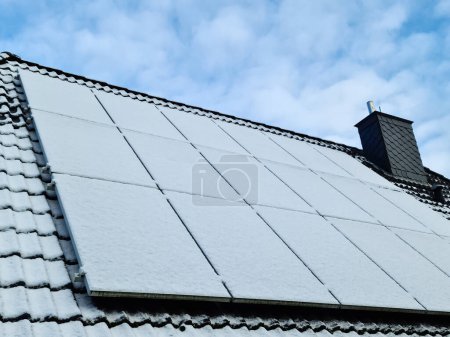 Photo for Solar panels covered in snow during wintertime for clean energy on a roof of a residential house - Royalty Free Image