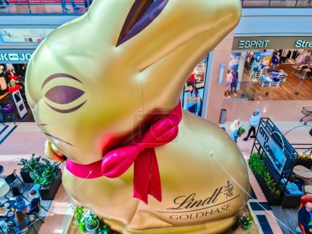 Téléchargez les photos : Kiel, Allemagne - 01. Avril 2024 : Un lapin géant doré de la marque de chocolat Lindt dans un centre commercial - en image libre de droit