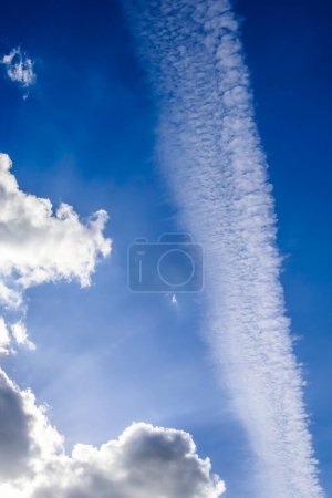 Flugzeugkondenswasser kondensiert am blauen Himmel zwischen ein paar schönen Wolken