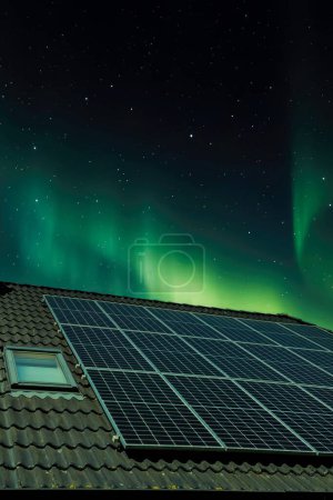 Solar panels producing clean energy on a roof of a residential house with aurora borealis in the background