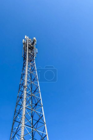 Photo for Electric antenna and communication transmitter tower in a european landscape against a blue sky - Royalty Free Image