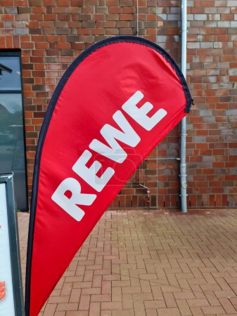 Photo for Kiel, Germany - 04. May 2024: A flag with the logo of the discount chain REWE in front of the entrance to a supermarket branch - Royalty Free Image