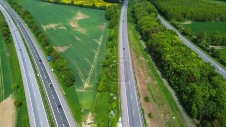Drone view of a highway in Germany with a lot of traffic and many green fields around it