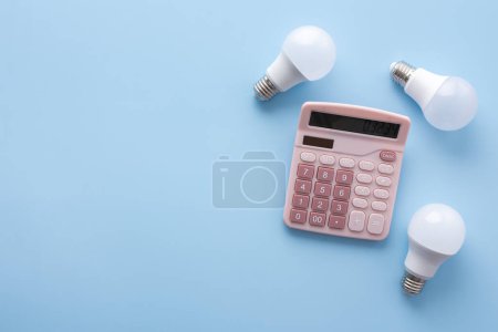 Photo for Save energy, accounting and saving money, energy saving light bulbs and notebook on a blue background, money spending planning, rising electricity costs, energy crisis in Europe - Royalty Free Image