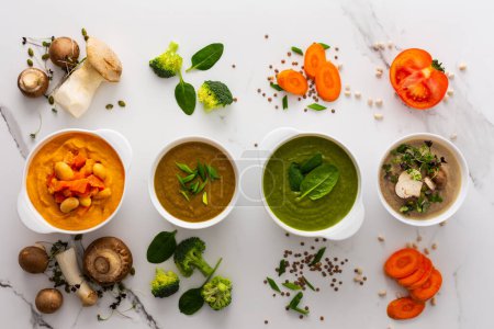 Mushroom and lentil cream soup, bean, carrot and tomato soup, broccoli and spinach soup on white background with cooking ingredients