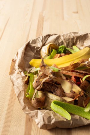 Foto de Residuos orgánicos de alimentos en papel pergamino ecológico, cáscara de frutas y verduras, clasificación y reciclaje de basura - Imagen libre de derechos