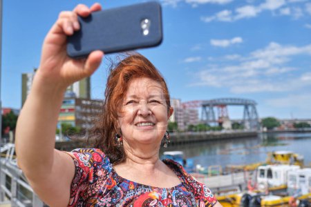 Téléchargez les photos : Touriste féminine faisant un autoportrait avec son téléphone portable dans le quartier touristique de La Boca, à Buenos Aires, Argentine, par une journée ensoleillée d'été. - en image libre de droit