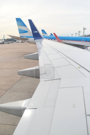 Foto de Buenos Aires, Argentina, 18 de noviembre de 2022: Vista desde una ventana sobre el ala de un avión Boeing 737-700 de Aerolineas Argentinas en la zona de embarque del Aeropuerto Internacional Jorge Newbery, - Imagen libre de derechos