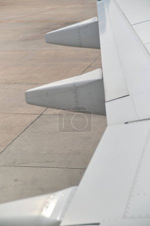 Foto de Detalle de un ala de un avión comercial de pasajeros estacionado, vista desde una ventana. Imagen minimalista para el concepto de viaje. - Imagen libre de derechos