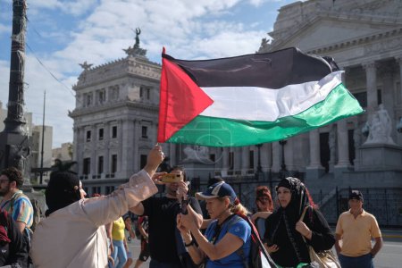 Foto de Buenos Aires, Argentina, 16 de febrero de 2024: Mujer levantando una bandera palestina, la gente se reunió frente al Congreso Nacional en solidaridad con Palestina y contra el ataque y genocidio de Israel. - Imagen libre de derechos