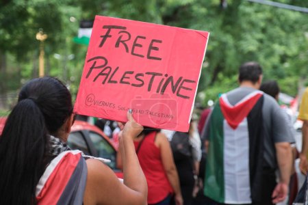 Foto de Buenos Aires, Argentina, 16 de febrero de 2024: personas marchando en solidaridad con Palestina contra el ataque genocida de Israel. Mujer irreconocible sosteniendo un cartel rojo con el texto Palestina Libre. - Imagen libre de derechos