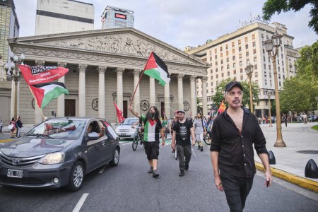 Foto de Buenos Aires, Argentina, 16 de febrero de 2024: Caravana de personas que protestan por el centro de la ciudad con carteles pacifistas y banderas palestinas en solidaridad con Palestina y contra el ataque genocida de Israel. - Imagen libre de derechos