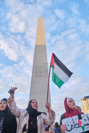 Foto de Buenos Aires, Argentina, 16 de febrero de 2024: Mujeres protestando frente al obelisco, en el centro de la ciudad, con carteles pacifistas y banderas palestinas en solidaridad con Palestina y contra el ataque genocida de Israel. - Imagen libre de derechos