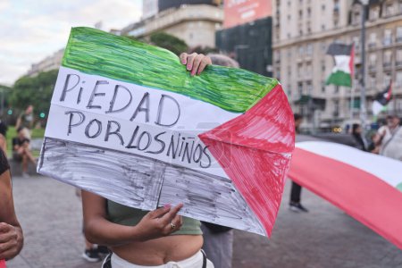 Foto de Buenos Aires, Argentina, 16 de febrero de 2024: personas protestando en solidaridad con Palestina contra el ataque genocida de Israel. Mujer irreconocible sosteniendo un cartel con el texto Misericordia para los niños. - Imagen libre de derechos